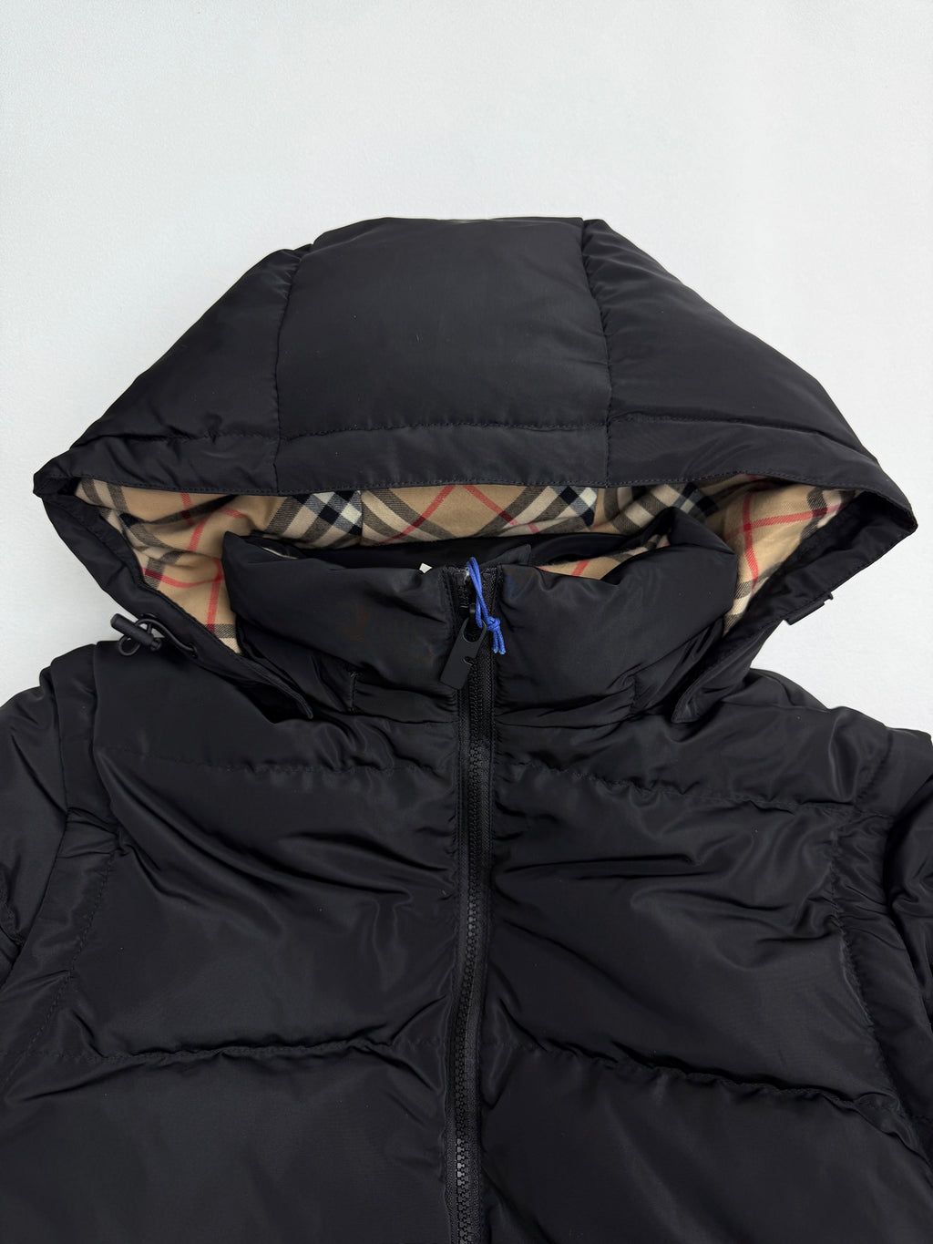 Black puffer jacket hood with plaid lining and concealed drawstring