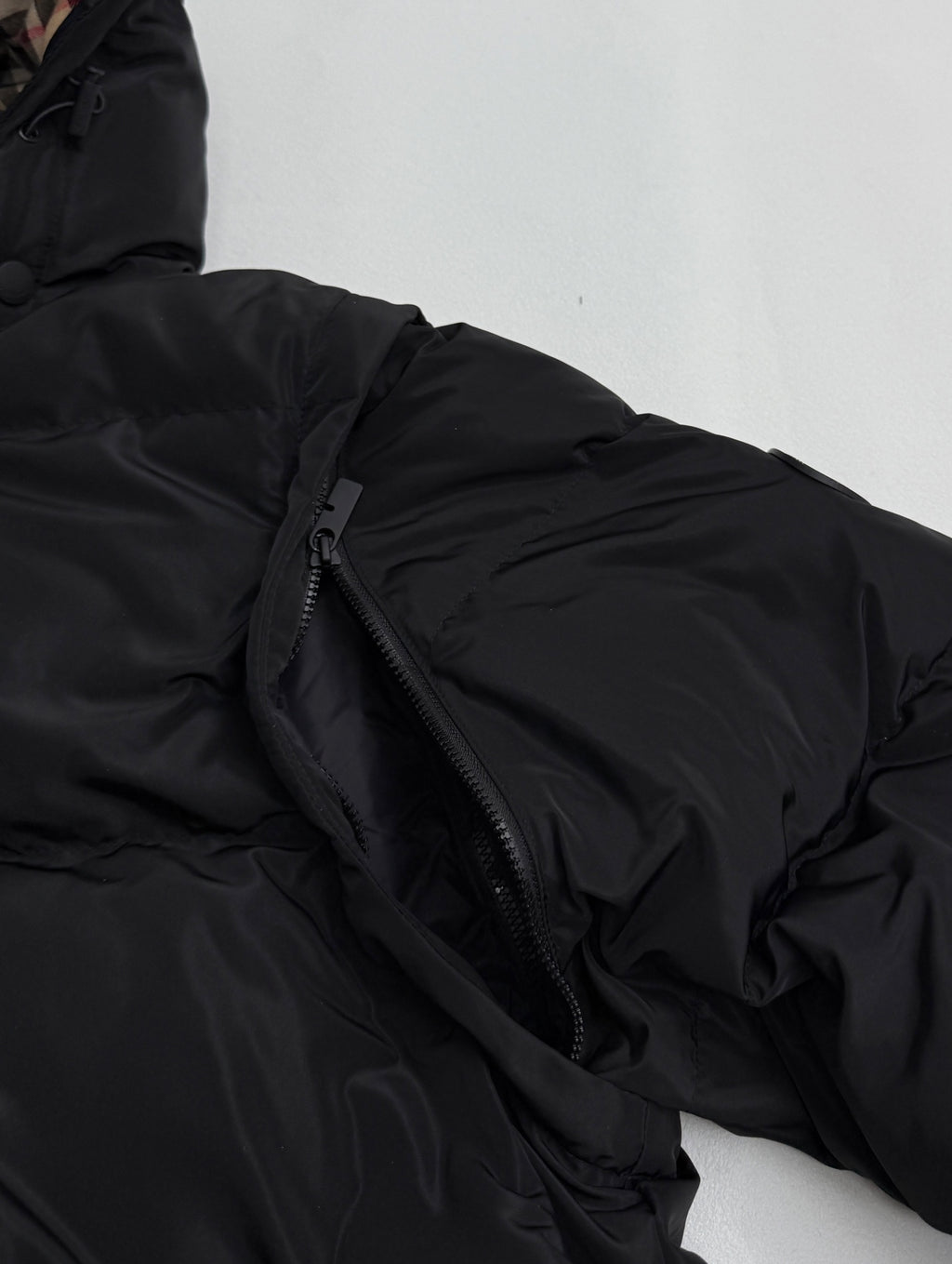Black jacket zipper and quilted fabric detail on a padded sleeve