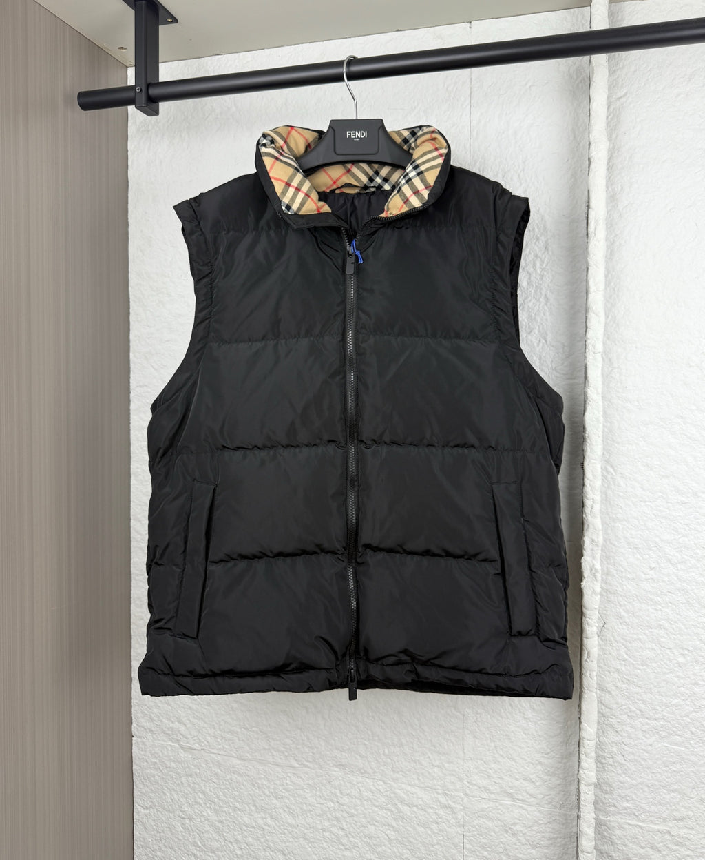 Black hooded puffer vest with plaid-lined hood, front view