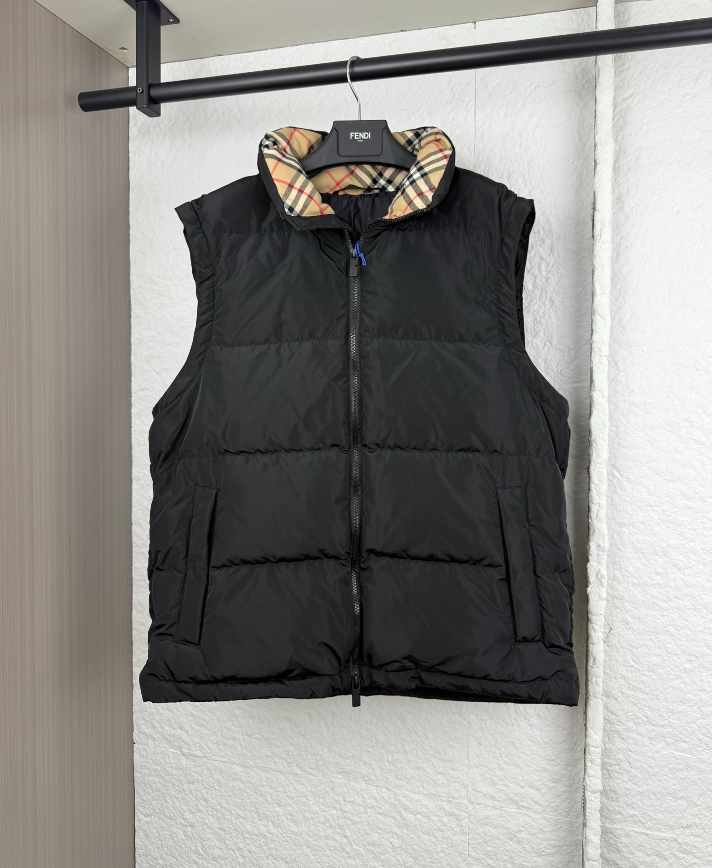 Black hooded puffer vest with plaid-lined hood, front view