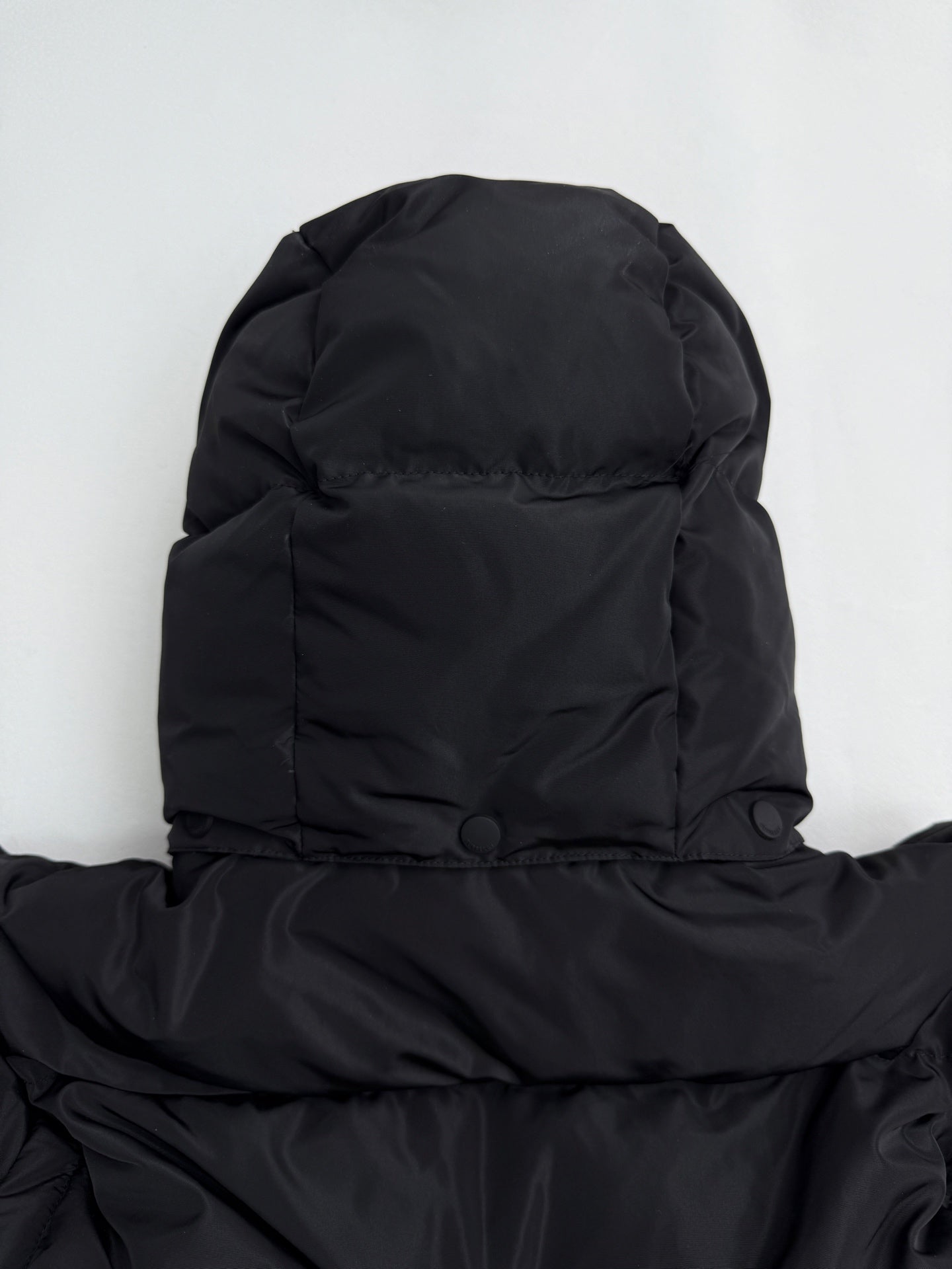 Black long puffer jacket hood and shoulder area with buttoned neck