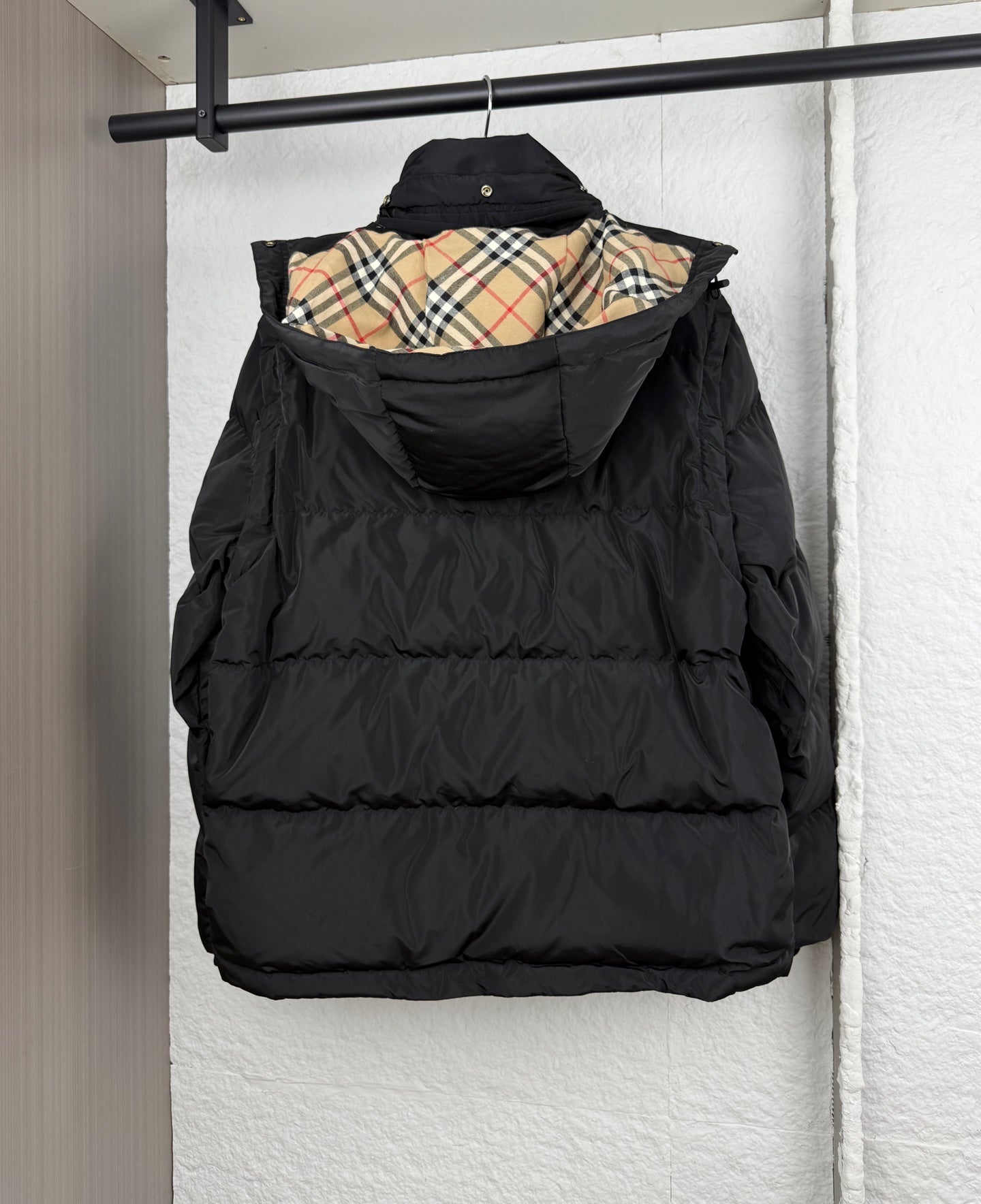Black hooded puffer jacket with plaid-lined inner hood, front view