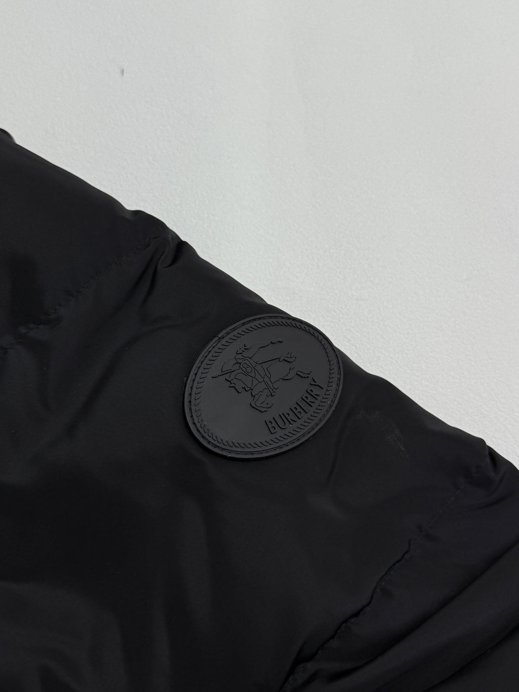 Black jacket shoulder with circular embossed Burberry patch