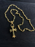 Gold-tone cross pendant necklace with green stone accents, chain loop clasp