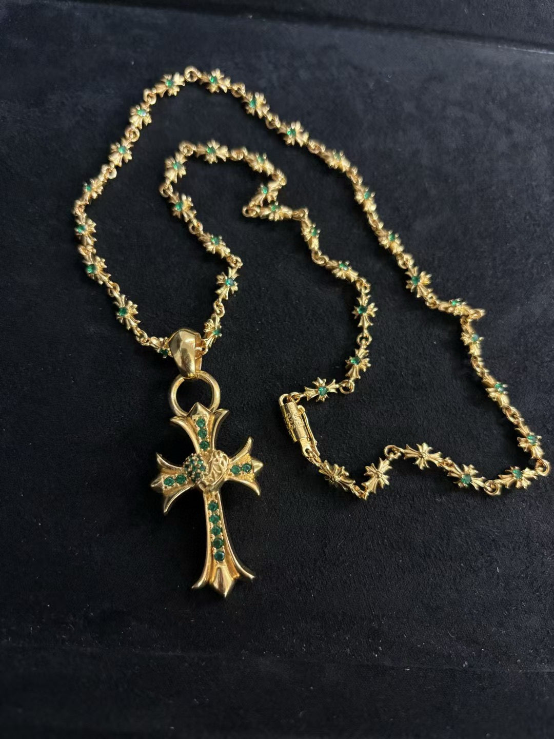 Gold-tone cross pendant necklace with green stone accents, chain loop clasp