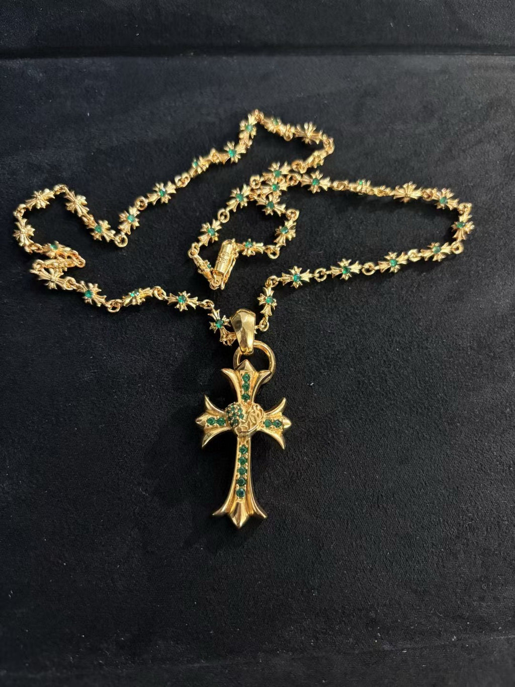 Gold-tone cross pendant necklace with green stones, layered chain and hook clasp