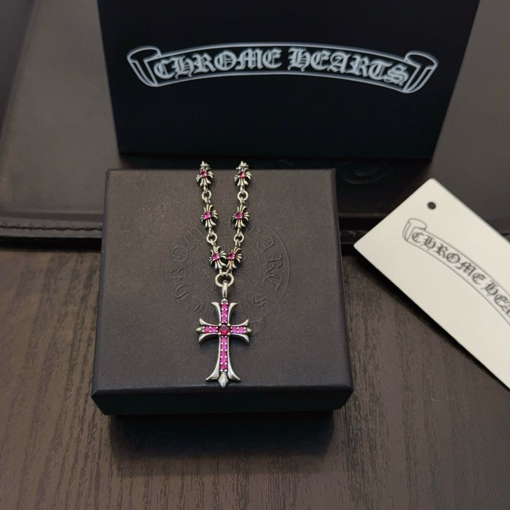 Silver-tone cross pendant necklace with pink crystal center and detailed chain links