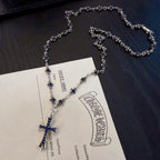 Silver-tone cross pendant necklace with blue inlay, laid out with matching chain.