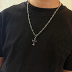 Silver-tone cross pendant necklace worn on a black shirt, with blue inlay charm.