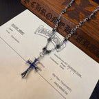 Silver-tone cross pendant necklace with blue inlay, laid on a product label card.