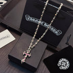 Silver cross pendant necklace with pink enamel accents on long chain links