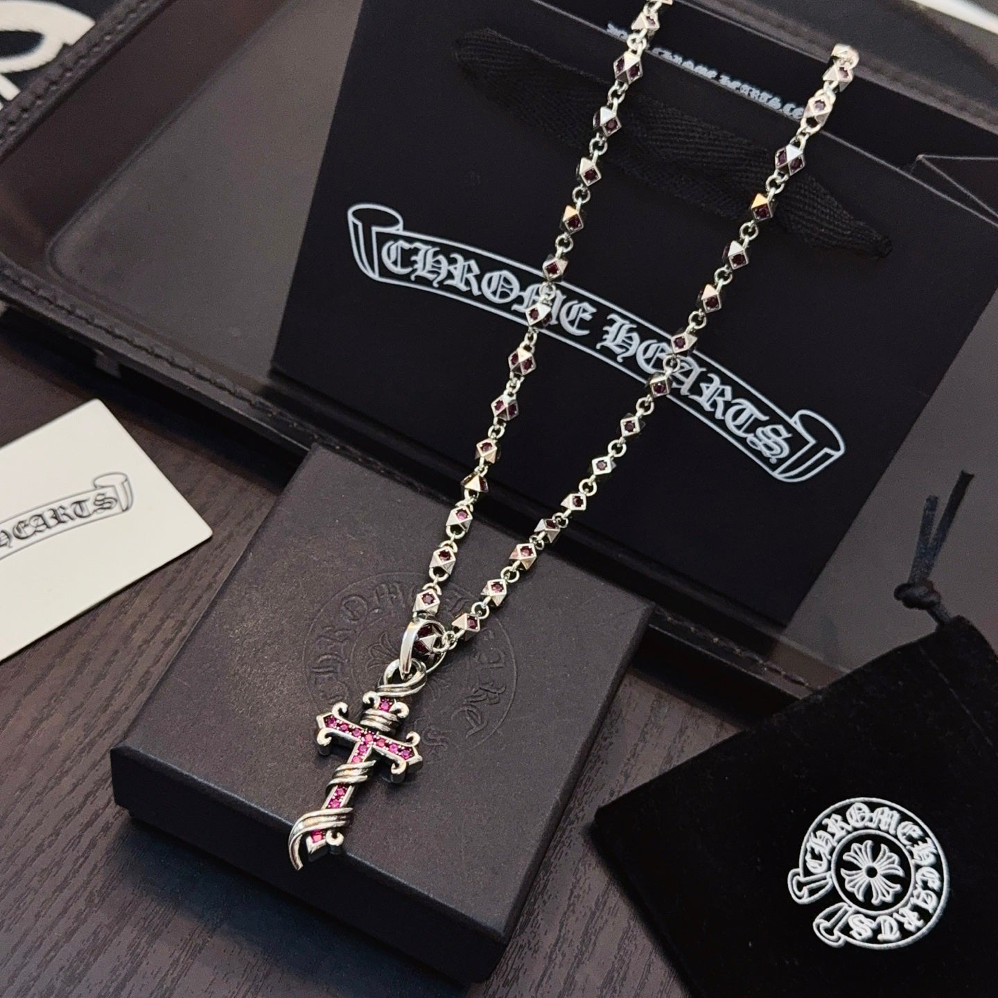 Silver cross pendant necklace with pink enamel accents on long chain links