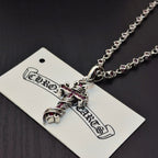 Cross pendant necklace with silver links and pink enamel accents, close-up