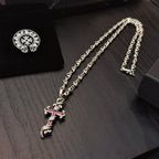 Silver cross pendant necklace with pink enamel accents on chain links