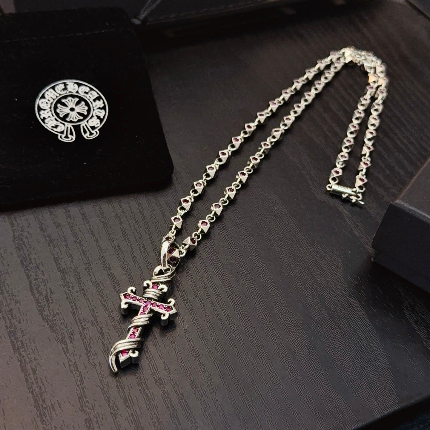 Silver cross pendant necklace with pink enamel accents on chain links