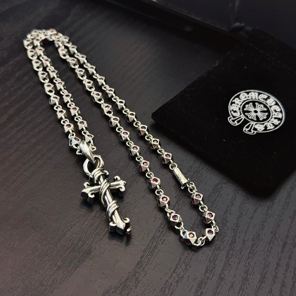 Silver cross pendant necklace with pink enamel accents on curb chain