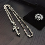 Silver cross pendant necklace with pink enamel accents on curb chain