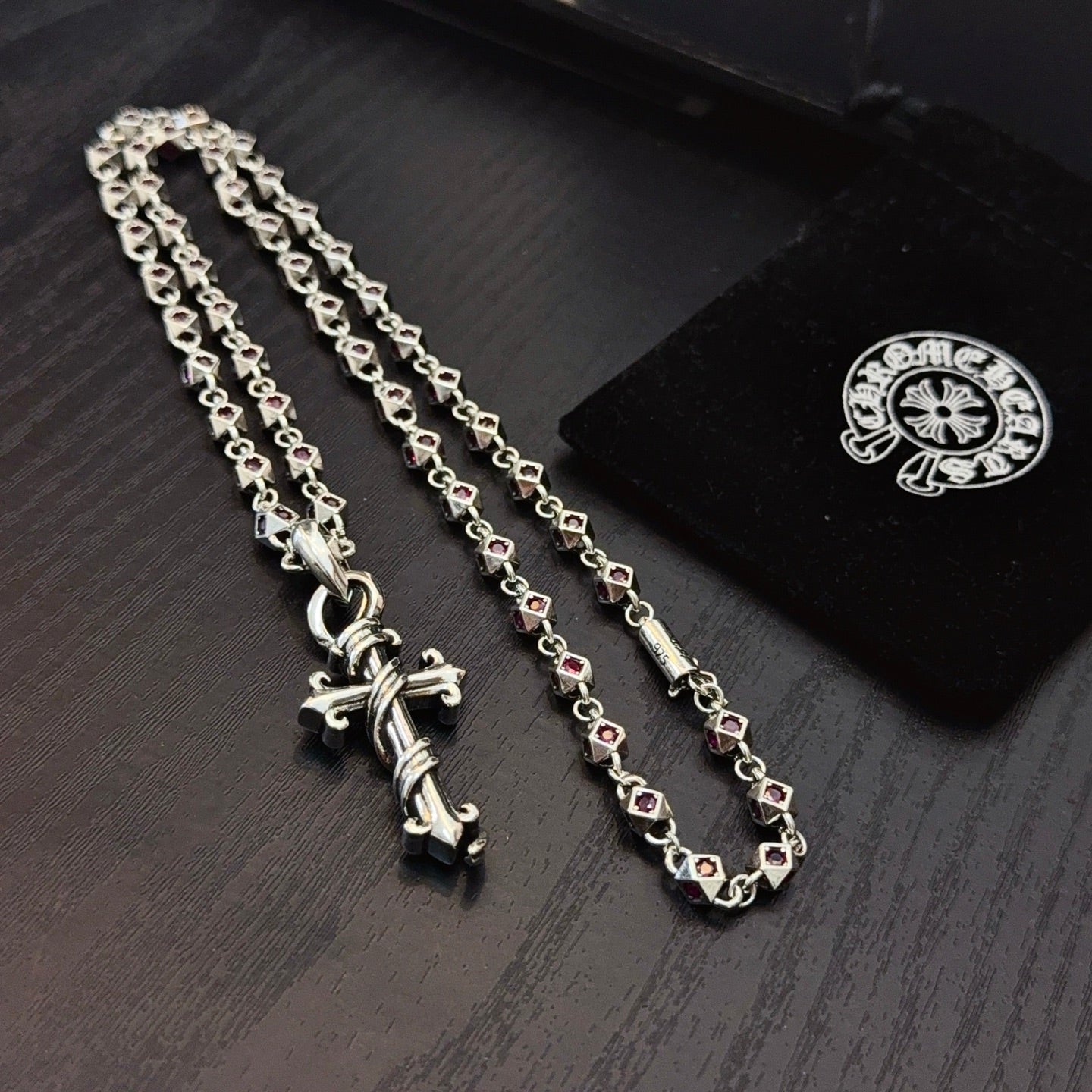 Silver cross pendant necklace with pink enamel accents on curb chain