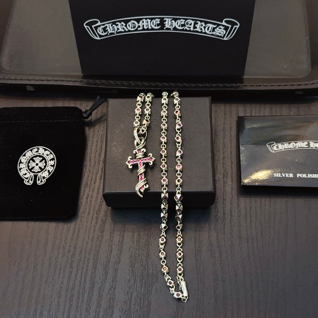 Silver cross pendant necklace with pink enamel accents and layered chain