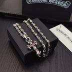 Silver cross pendant necklace with pink enamel accents on layered curb chains