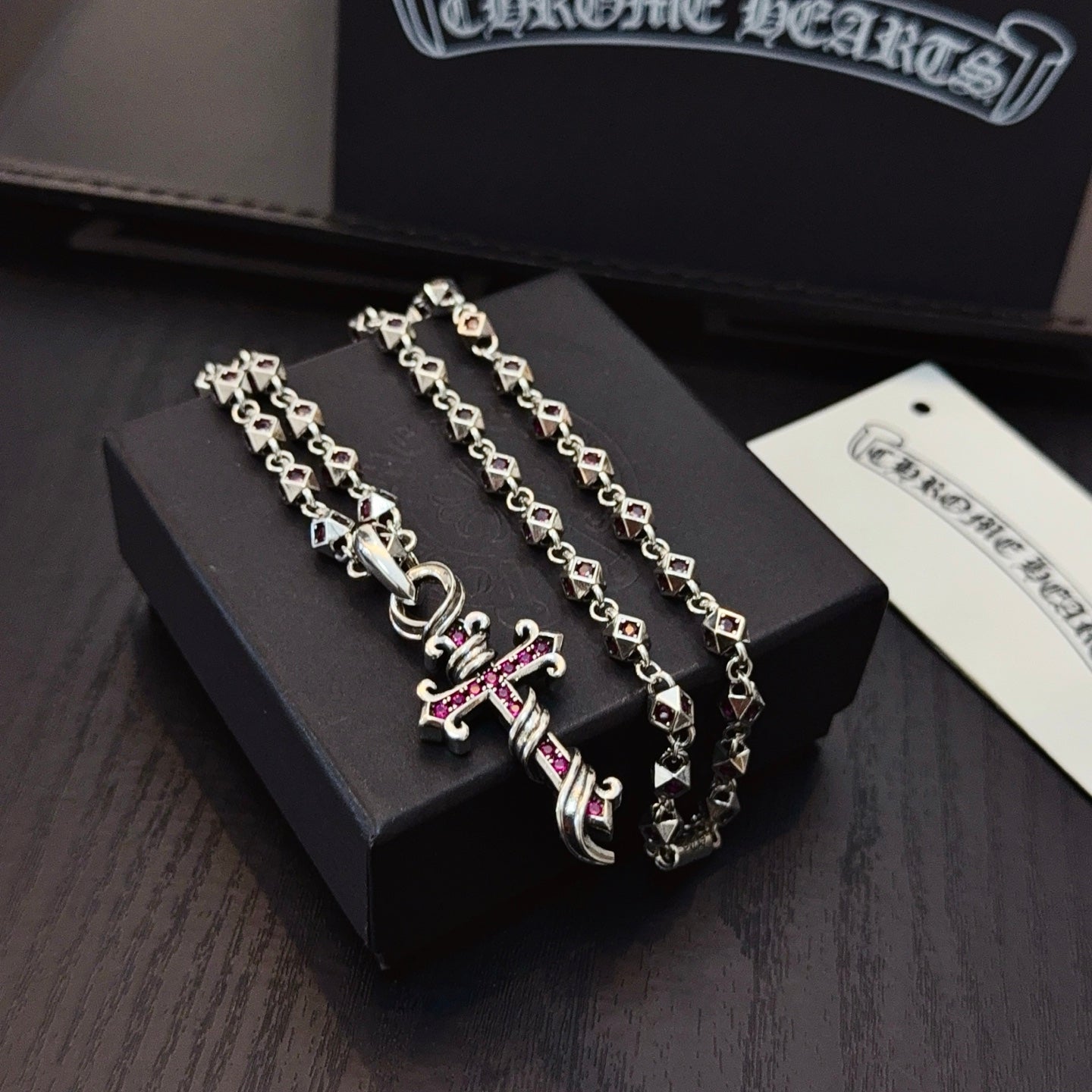 Silver cross pendant necklace with pink enamel accents on layered curb chains