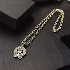 Chrome pendant necklace with round cross emblem pendant and silver-toned curb chain