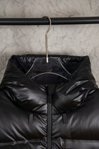 Hooded long puffer jacket hanging on rack, dark with front zip and sleeve tags