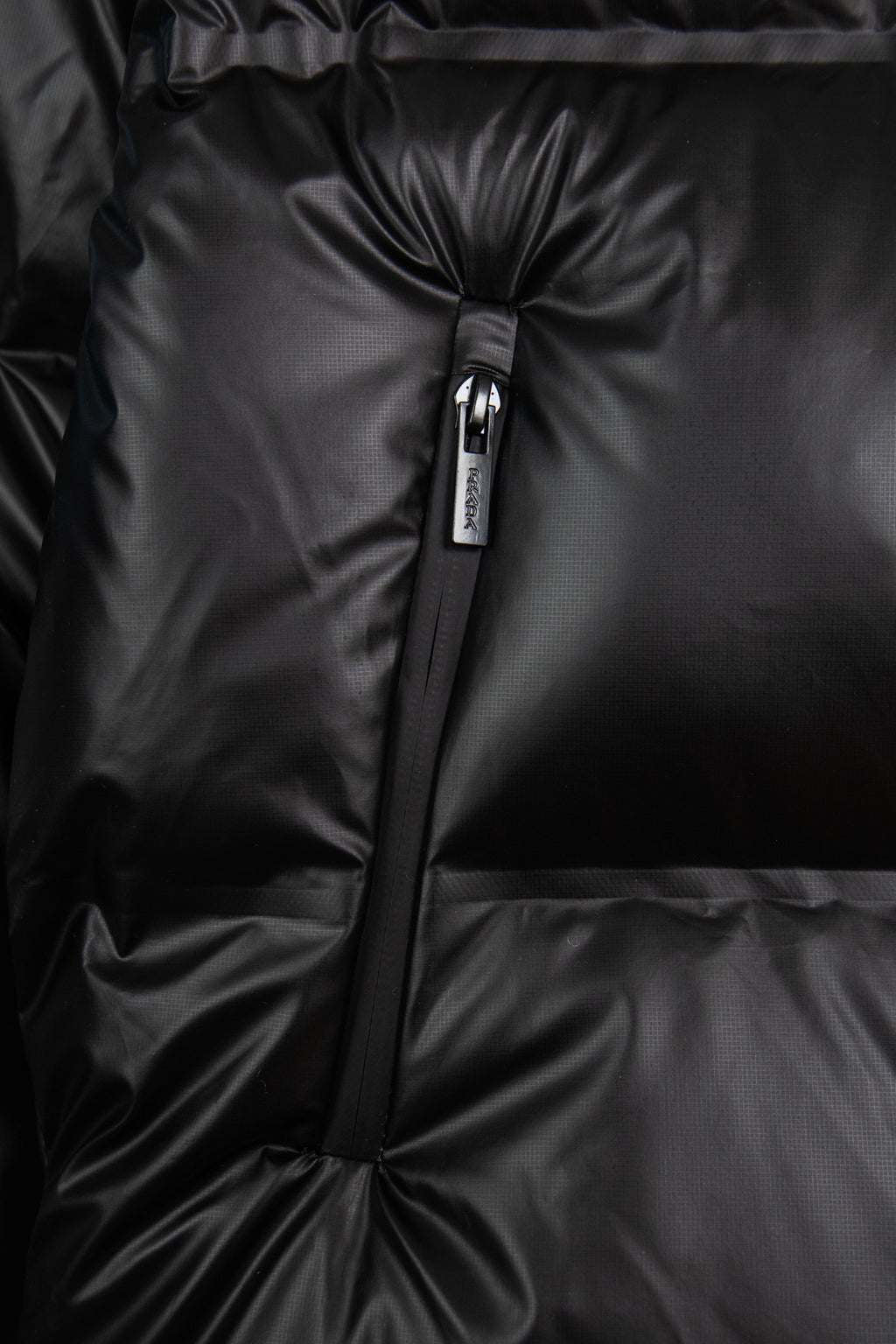 Front detail of dark puffer jacket zipper with quilted, puffed panels