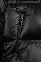 Front detail of dark puffer jacket zipper with quilted, puffed panels