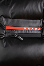 PRADA logo patch on front of dark puffer jacket with orange-red stripe