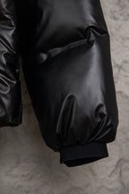 Long puffer jacket lower sleeve and cuff, dark glossy fabric with elastic hem