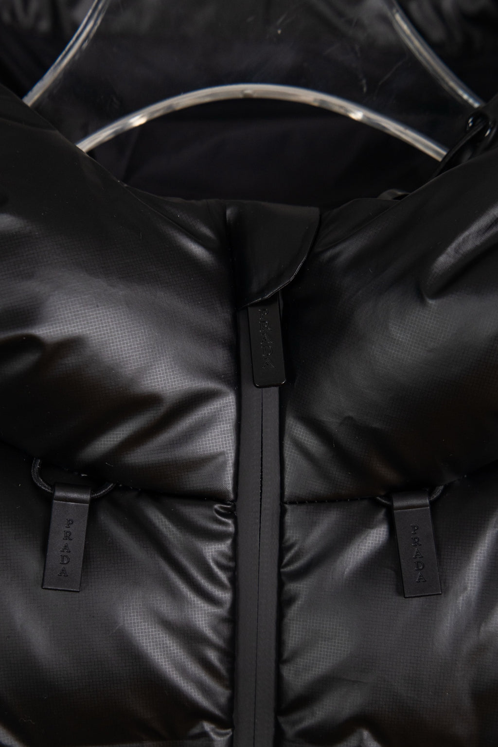 Puffer jacket close-up of front zipper and two branded snap/strap tabs