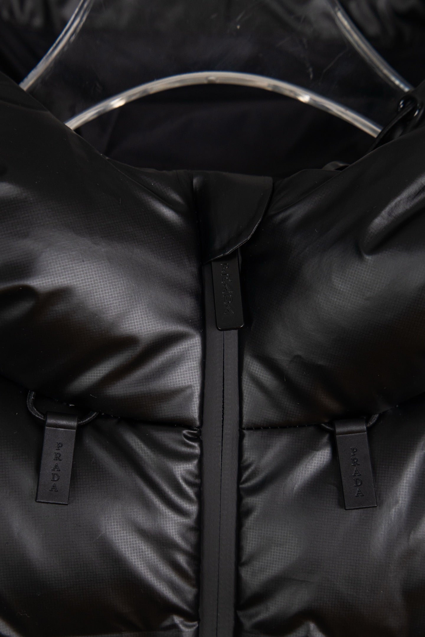 Puffer jacket close-up of front zipper and two branded snap/strap tabs