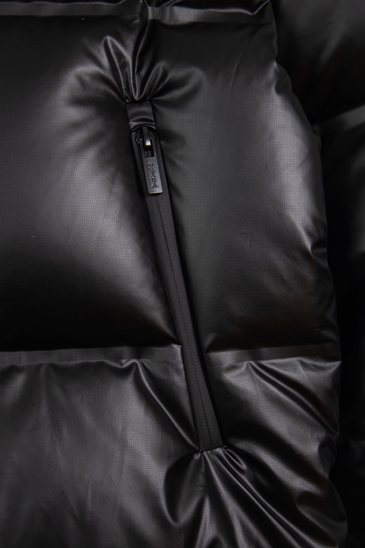 Dark puffer jacket front seam detail with center zipper and quilted panels
