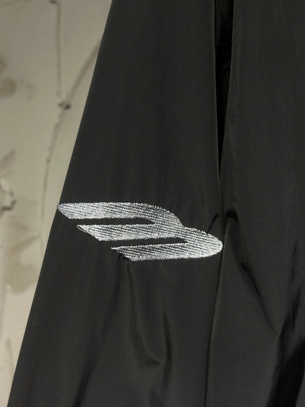 Black jacket sleeve with silver graphic logo detail