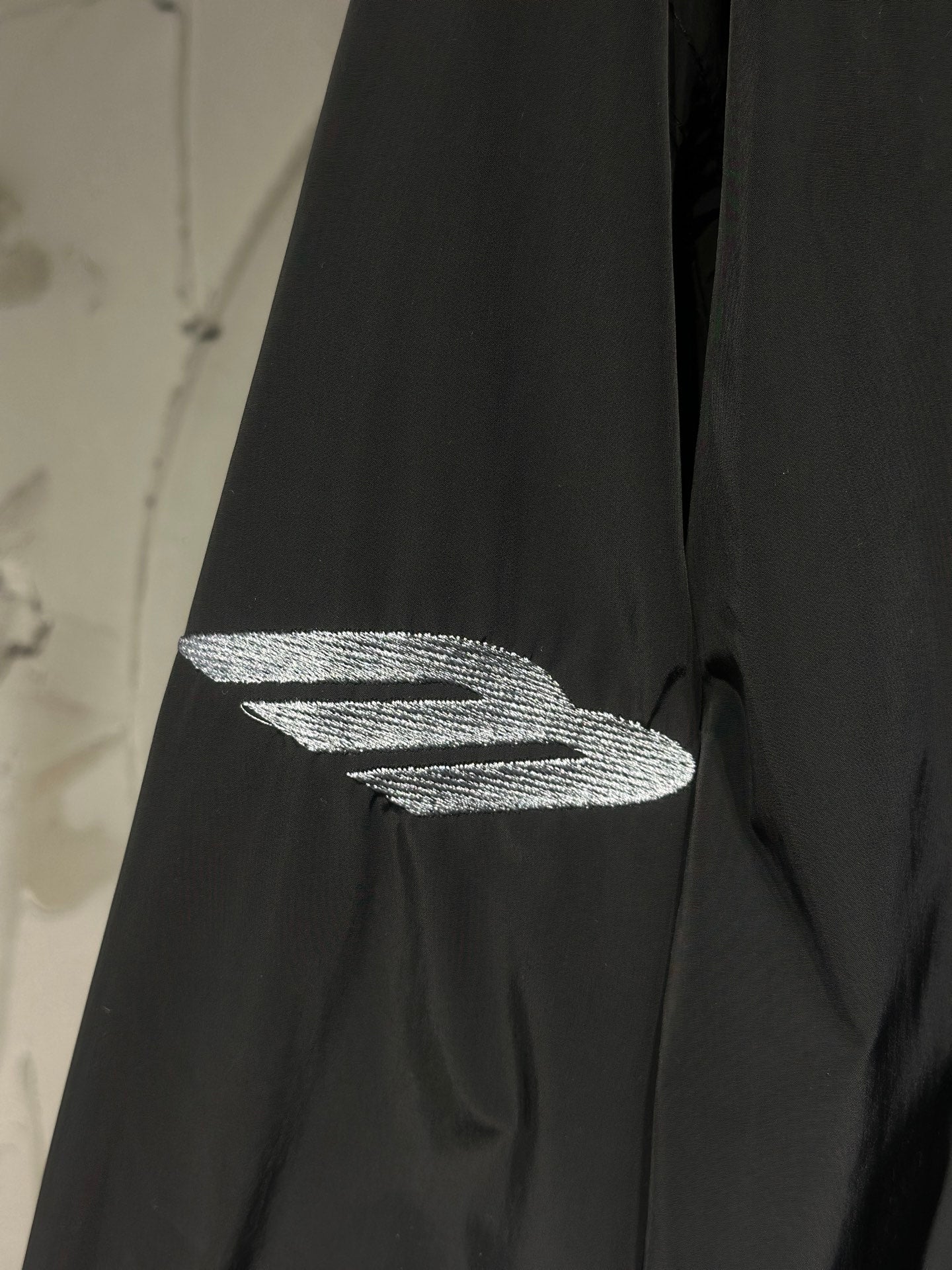 Black jacket sleeve with silver graphic logo detail
