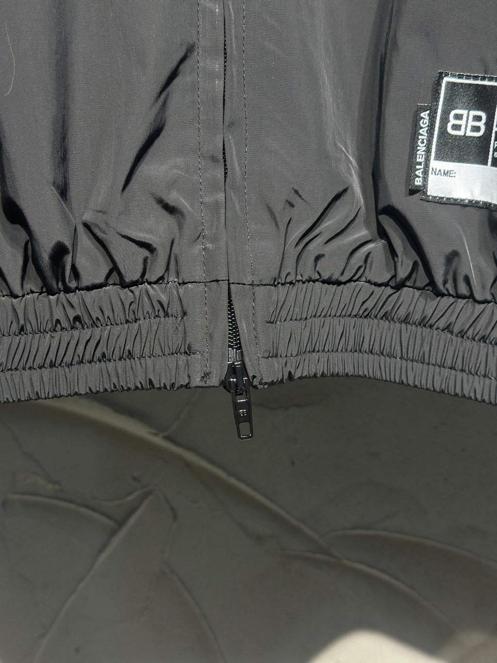 Black track jacket hem with gathered elastic and front zipper
