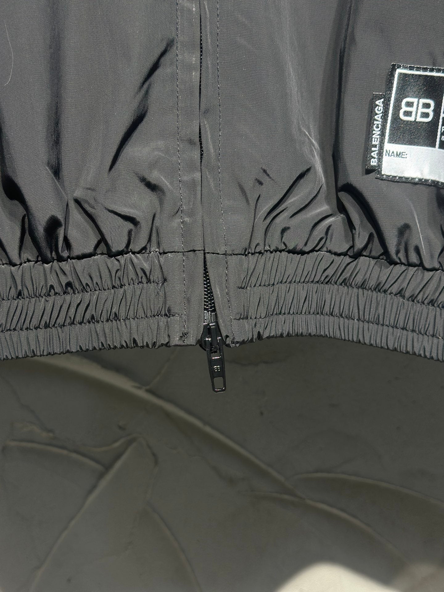 Black track jacket hem with gathered elastic and front zipper