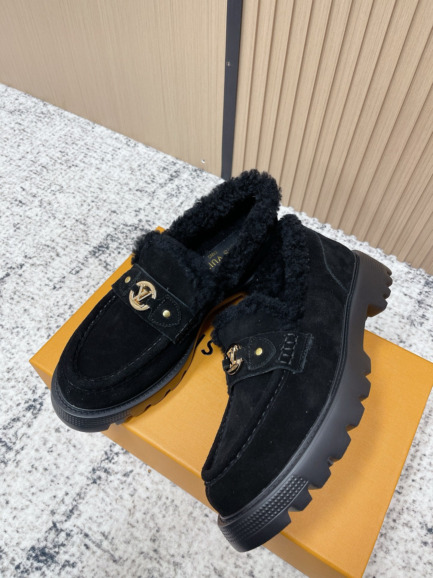 Dark suede shearling slip-on loafers with gold logo hardware and chunky rubber sole