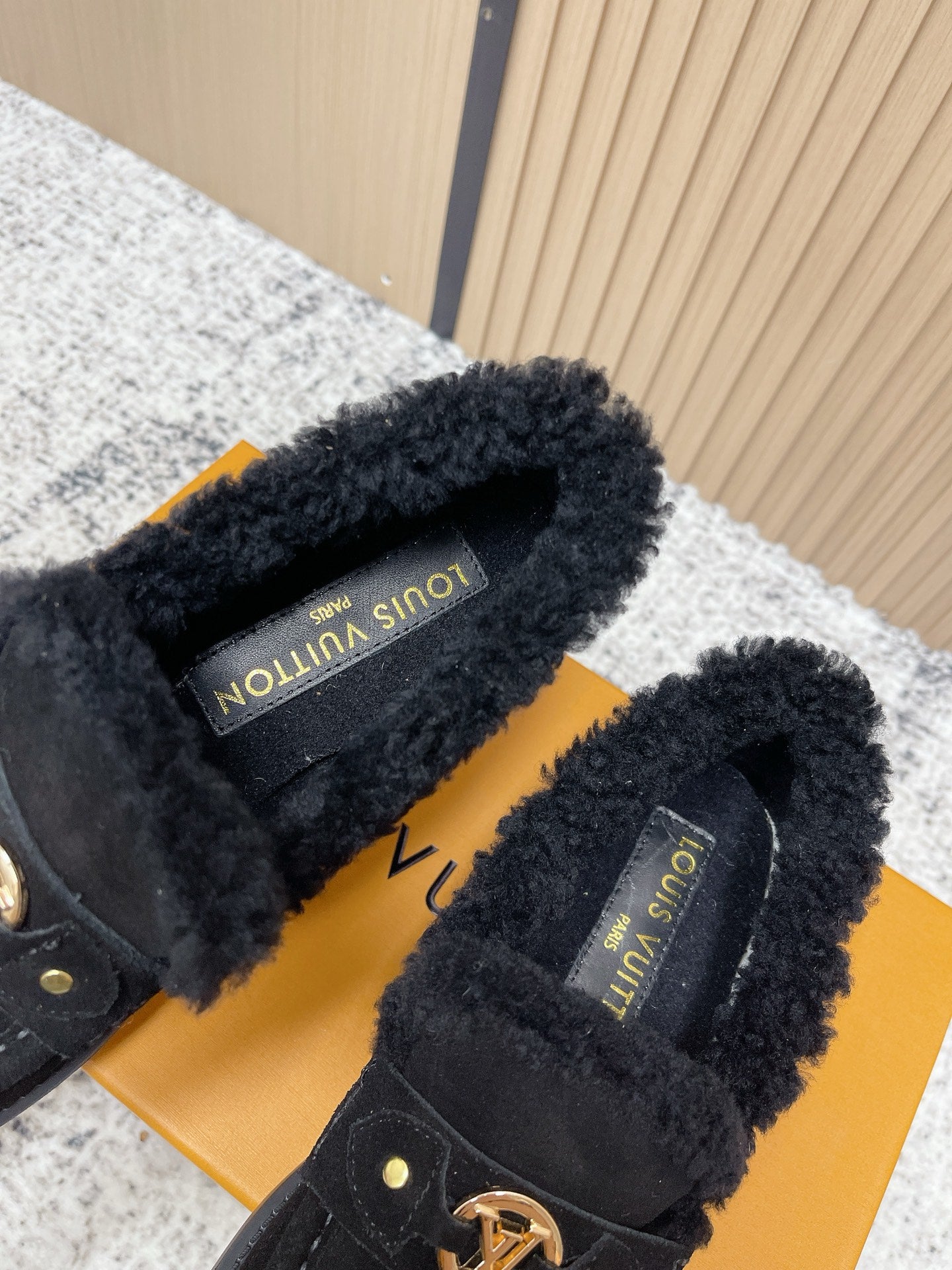 Shearling-lined interior of dark suede loafer shoes with printed brand label