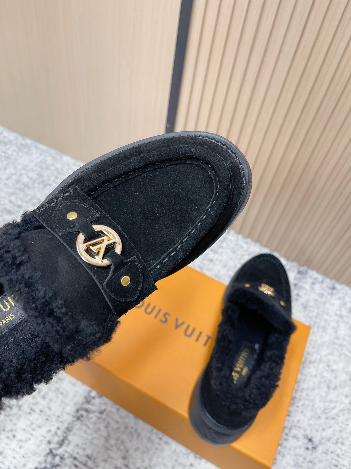 Dark suede loafer vamp with gold logo buckle hardware and shearling cuff