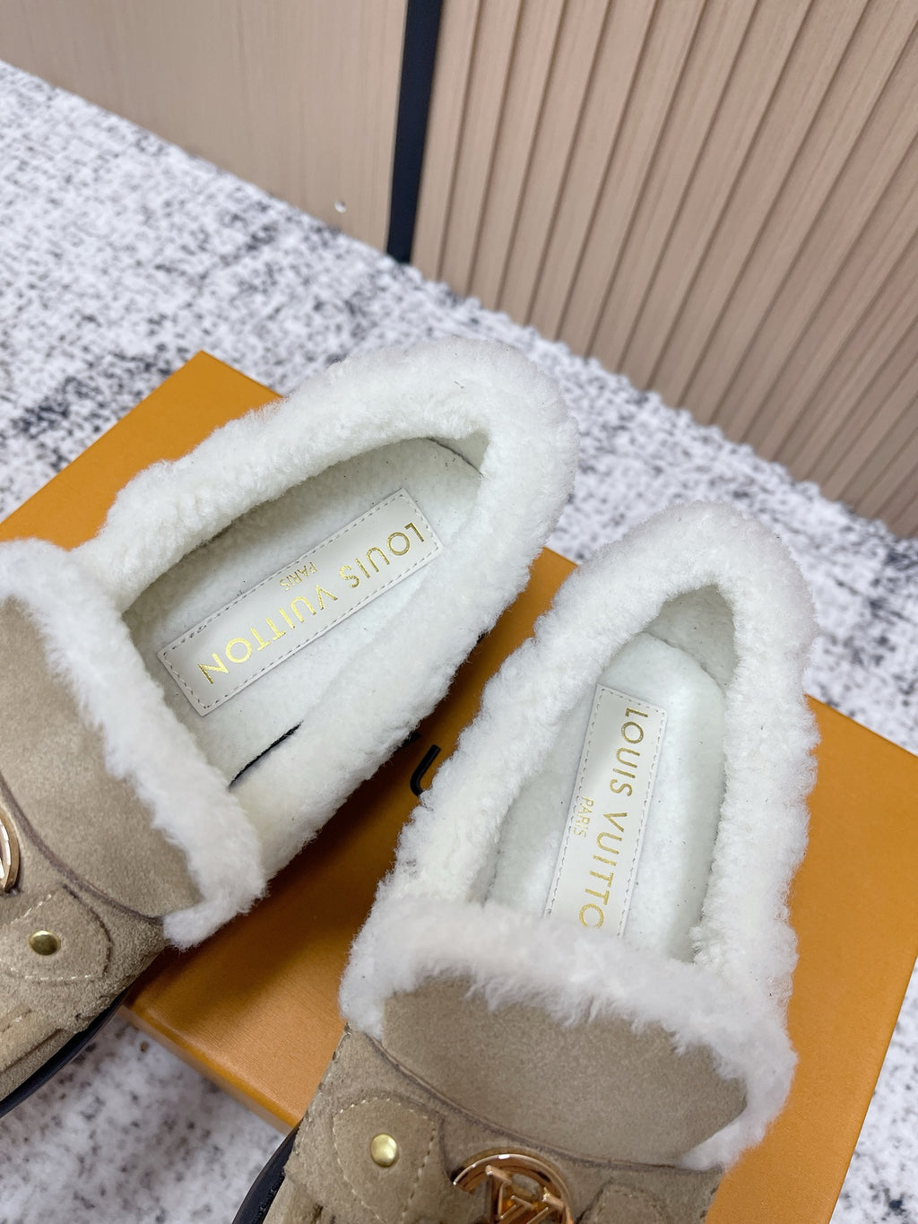 Inside view of beige slip-on shoes showing white shearling lining and stamped insole