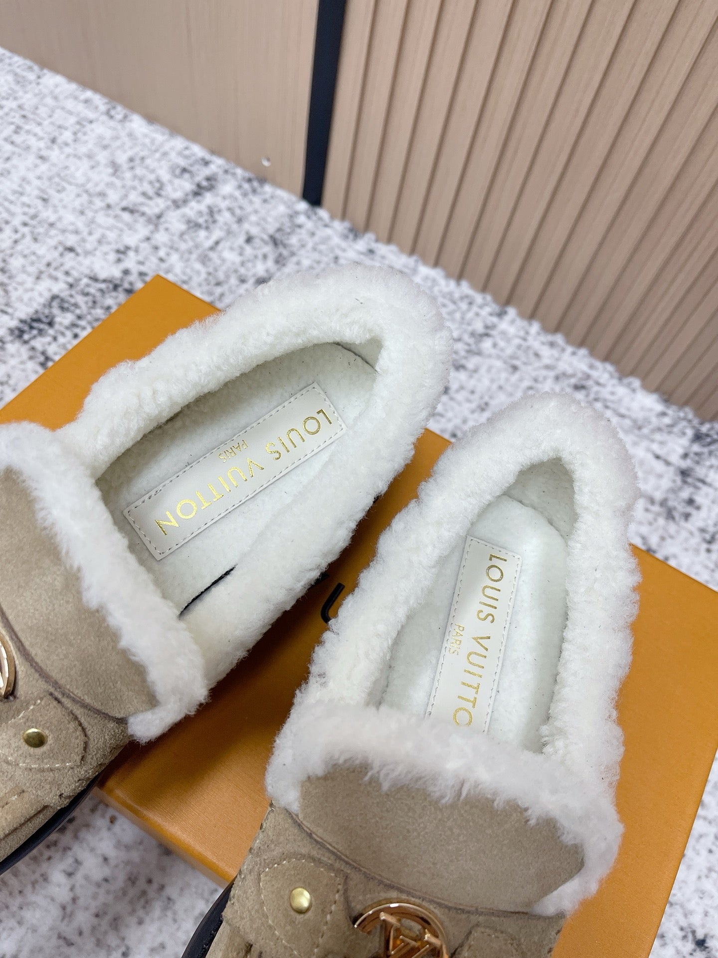 Inside view of beige slip-on shoes showing white shearling lining and stamped insole
