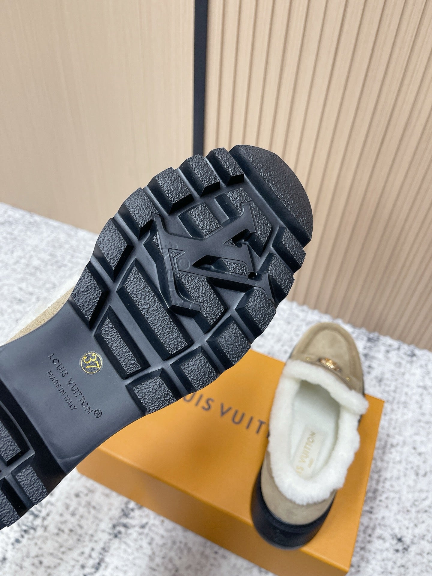Outsole view of beige shearling shoes with textured dark rubber tread