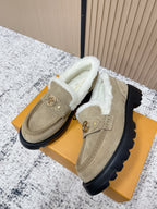 Beige shearling-lined slip-on shoes with gold hardware and thick black rubber sole