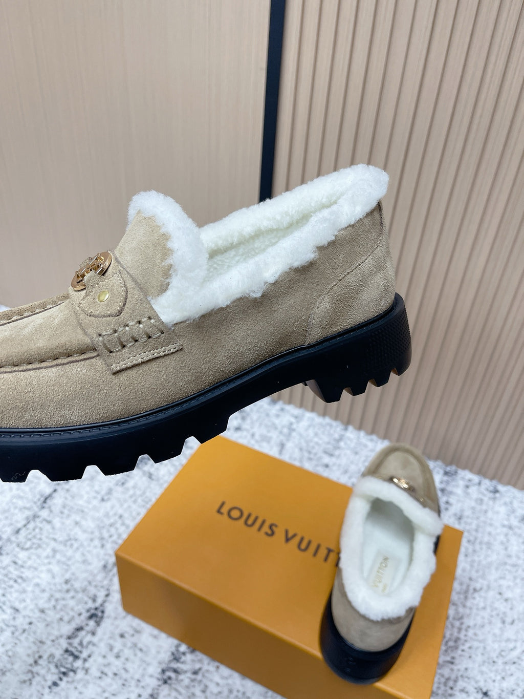 Beige suede slip-on shoes with white shearling trim and black sole tread detail