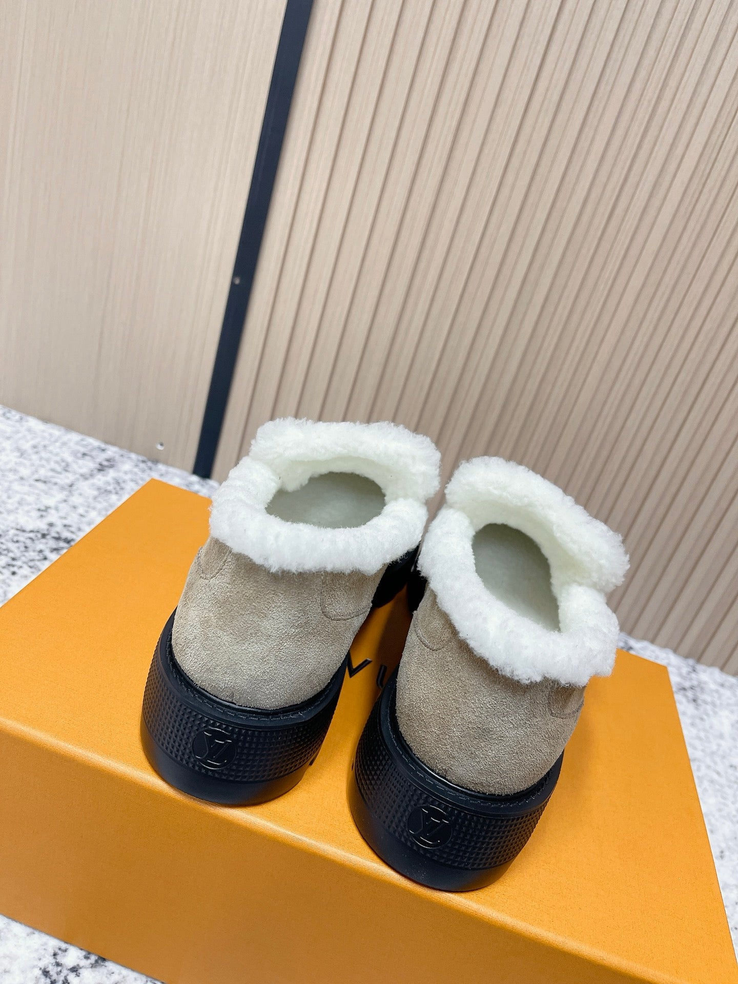 Beige suede slip-on shoes with white shearling collar and black sole