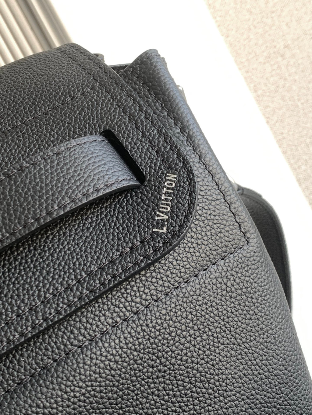 Black leather flap strap detail with Louis Vuitton logo stitching