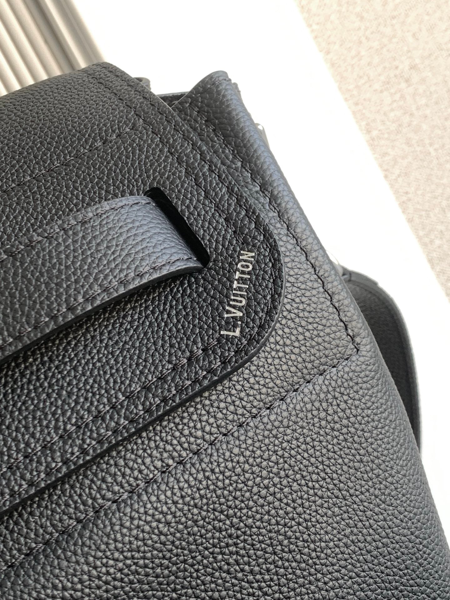 Black leather flap strap detail with Louis Vuitton logo stitching