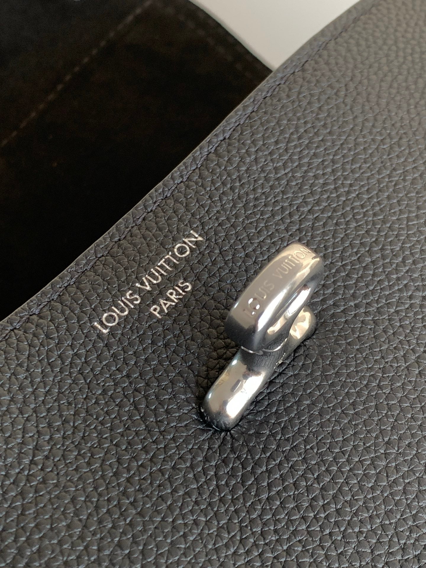 Black leather bag closure with Louis Vuitton Paris logo on metal clasp